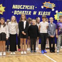 Grupa czwartoklasistów, którzy występowali w akademii stoi na tle dekoracji.
